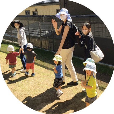園庭で先生と遊ぶ園児たち